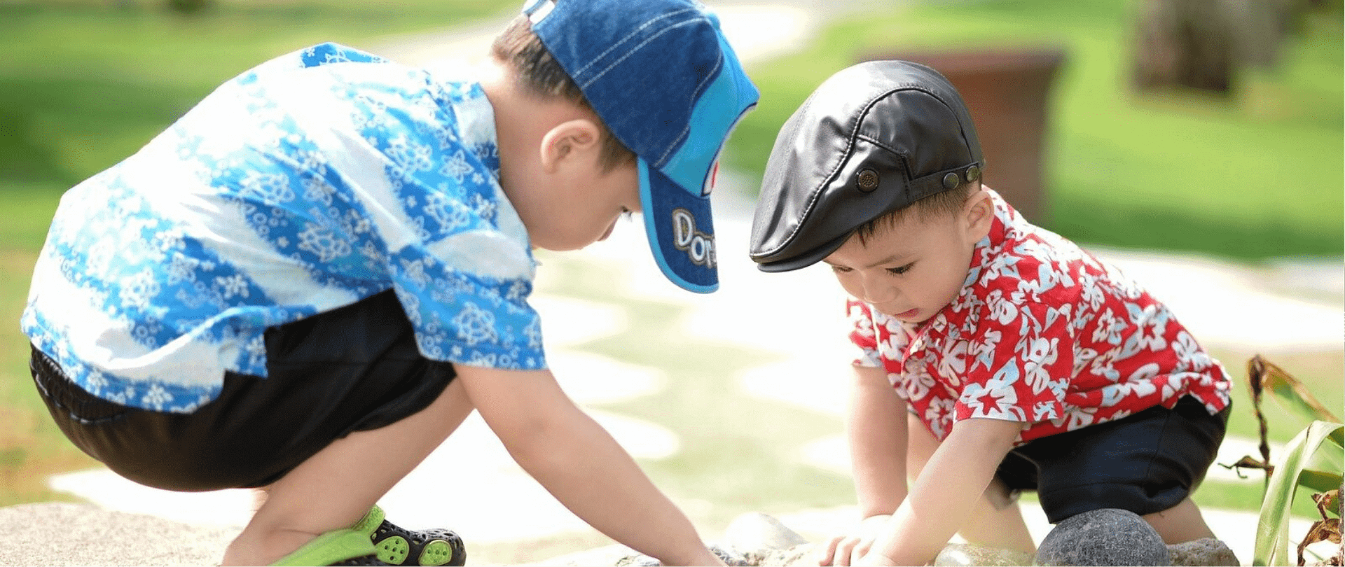 Two toddler boys crouched outdoors exploring together at Wooden Shoes Child Care Center